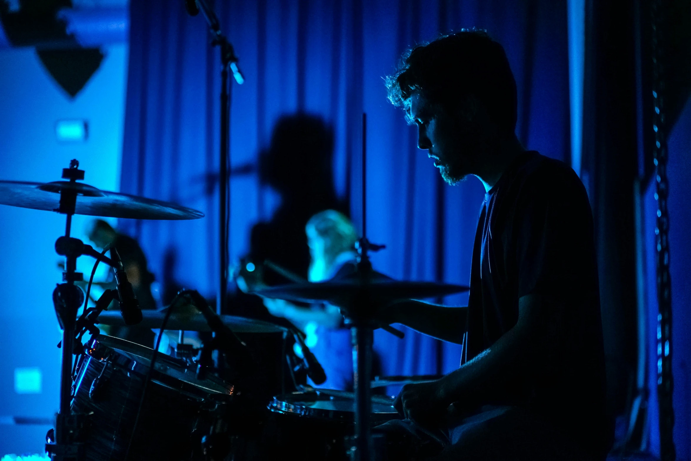 the drummer behind his drum set in front of microphones