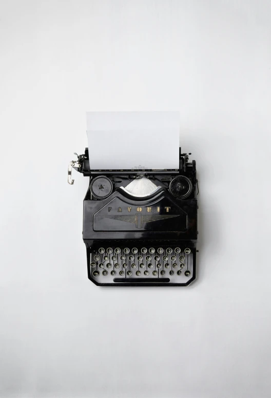 old fashioned black and silver typewriter with a white sheet