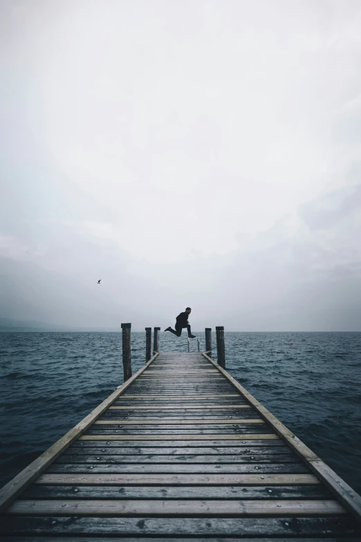 a man is sitting on a wooden pier with his dog