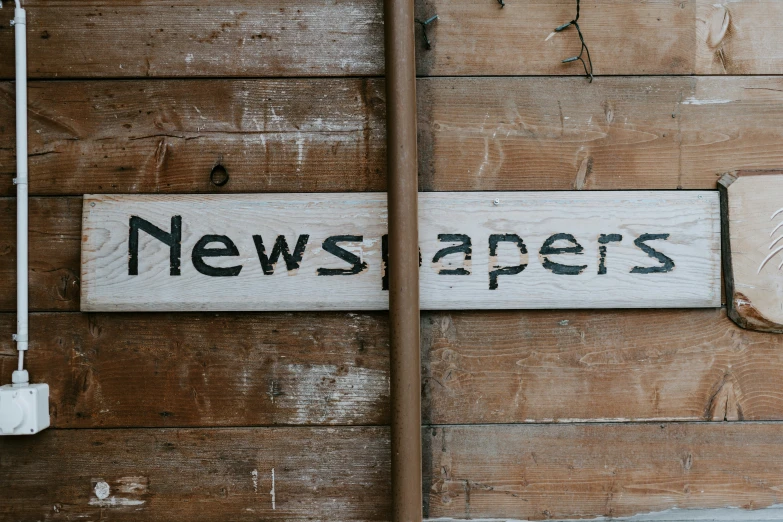 a news paper sign hanging on a wall