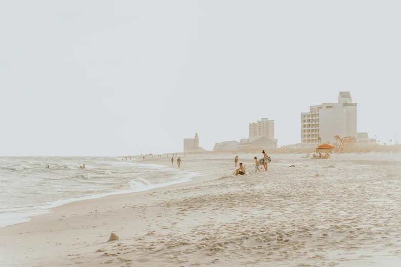 people on a beach, walking and riding their horses