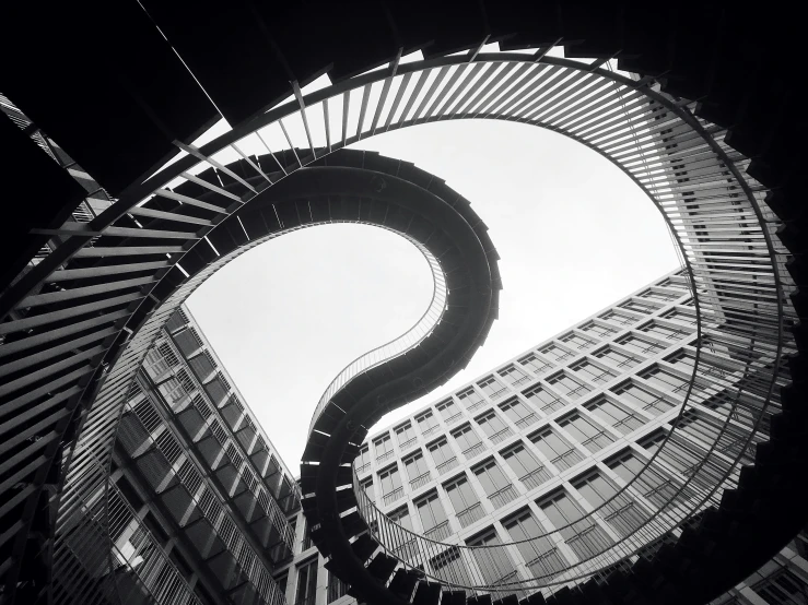 the spiral stairs in a modern building with a clock at each end