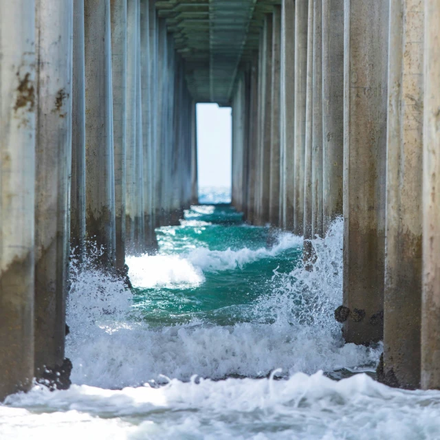 waves and crashing ocean spray beneath a pier