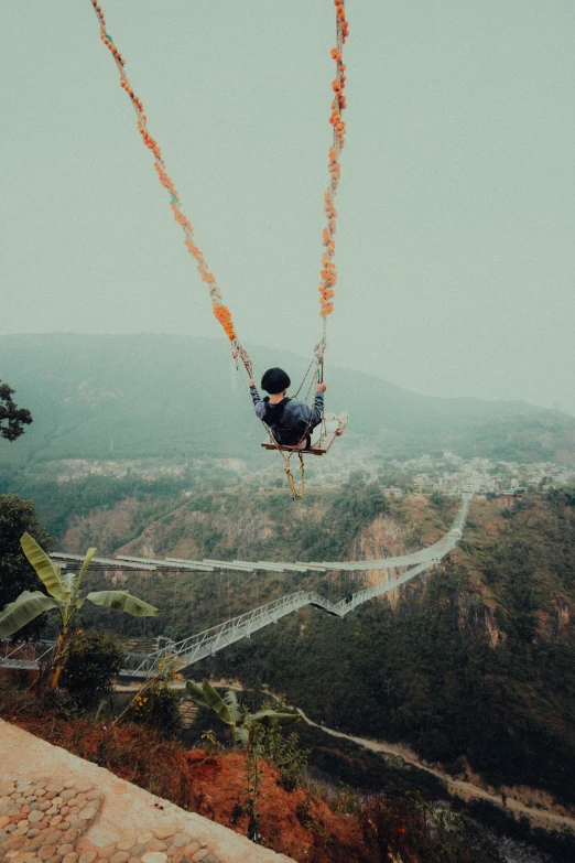 a man suspended from a rope in the middle of a valley