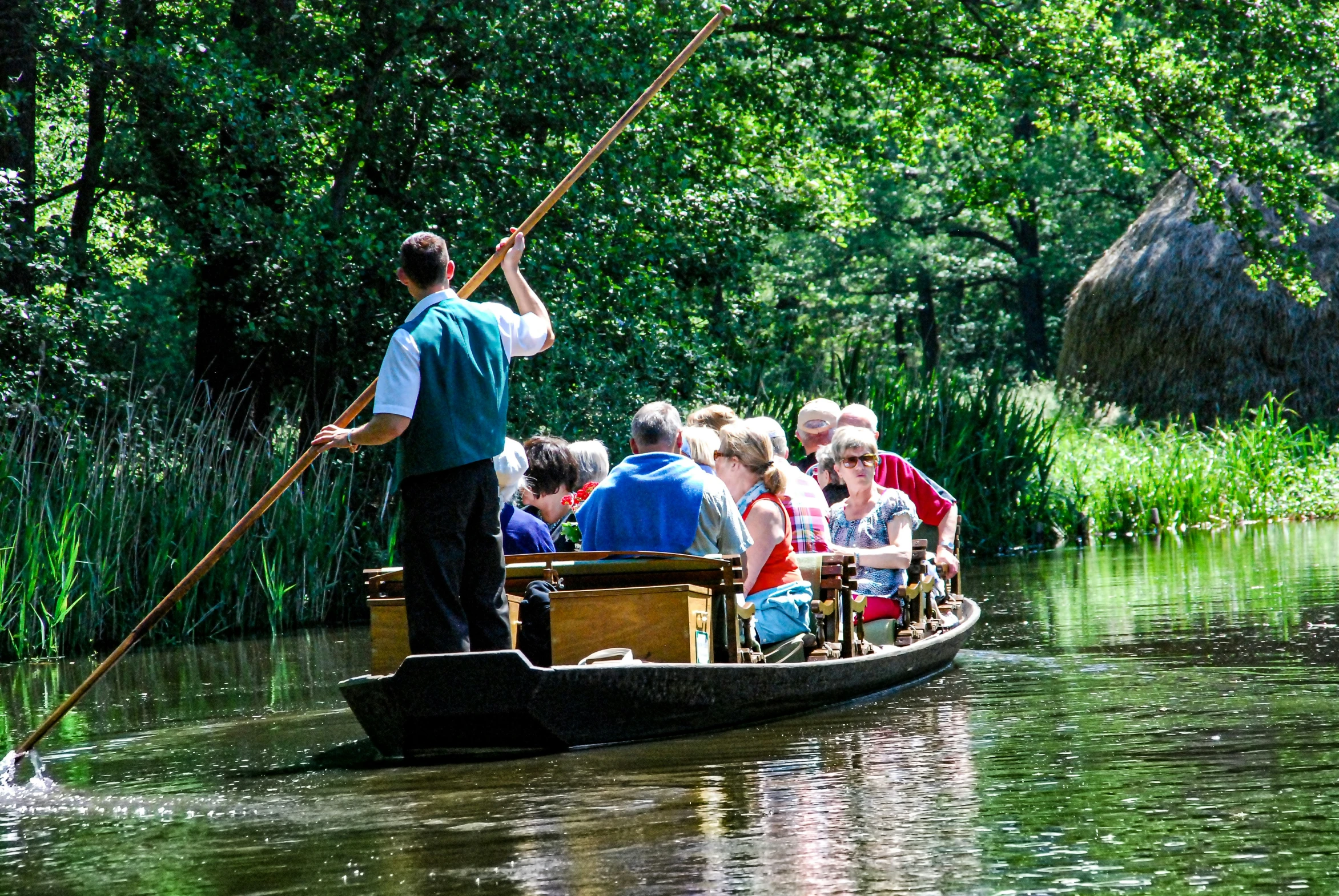 an older man holds up a spear as he paddles a boat