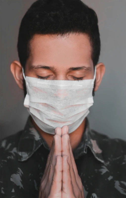 a man wearing a mask and praying while wearing his hands together