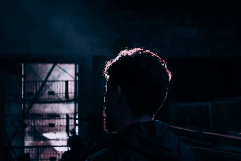 a man stares into the dark from under his jacket