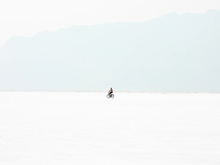 an image of man riding a bike across a vast field