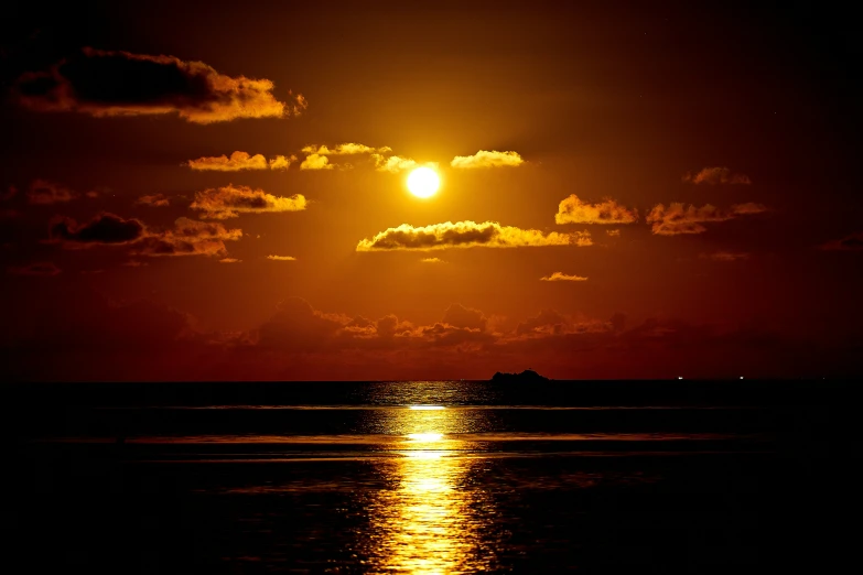 bright red light shines in the dark night sky above a body of water