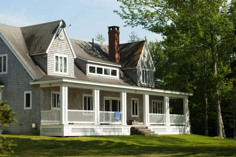 the front of a gray house with white trim and porches