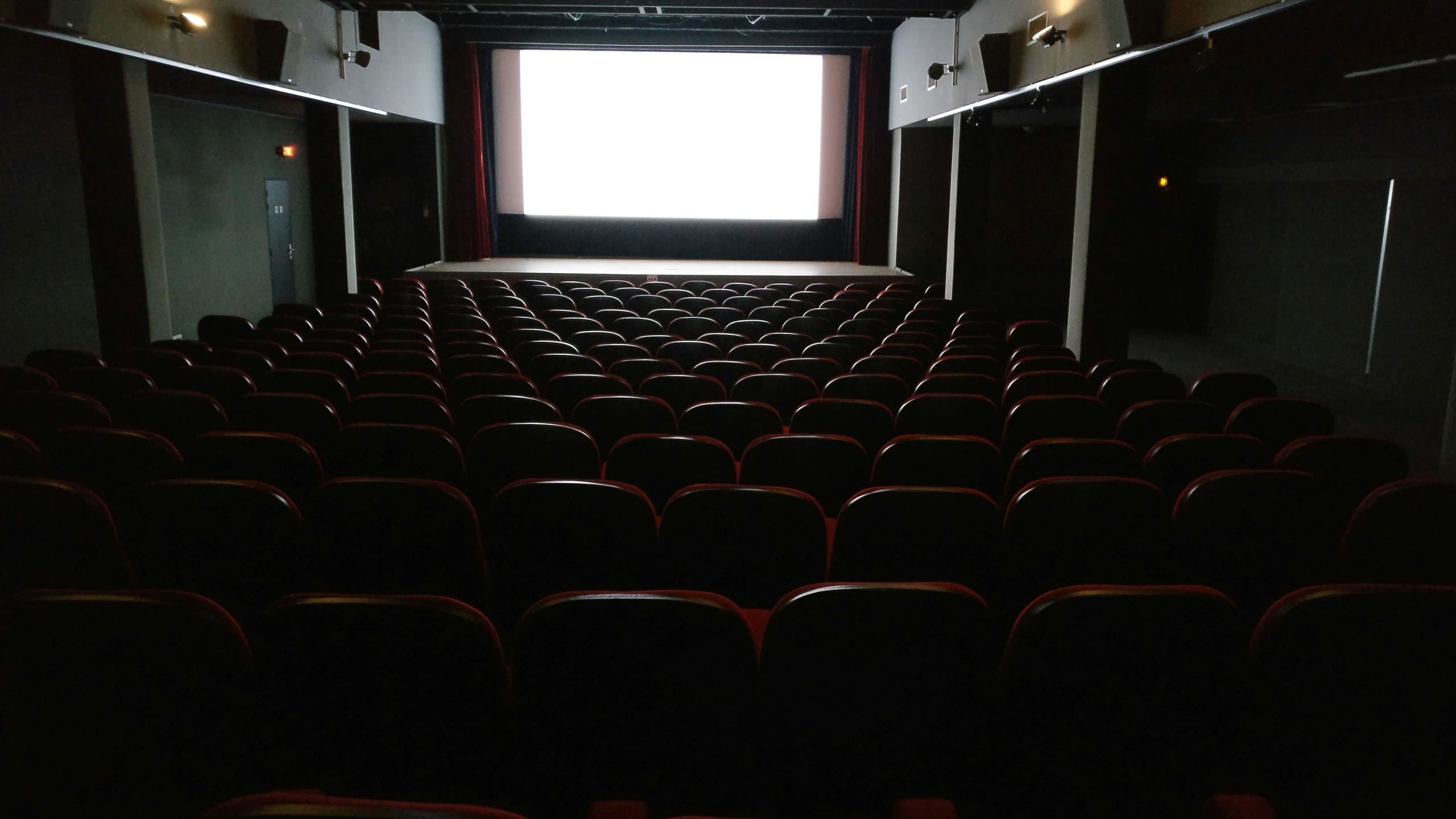 an empty auditorium room with rows of chairs and a flat screen