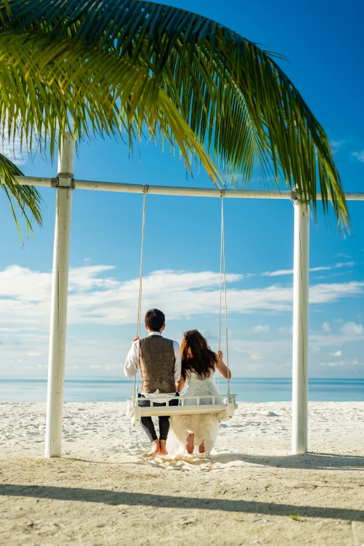 a bride and groom are sitting on a swing