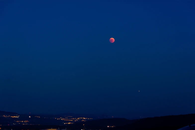 an airplane taking off at night with the moon in the distance