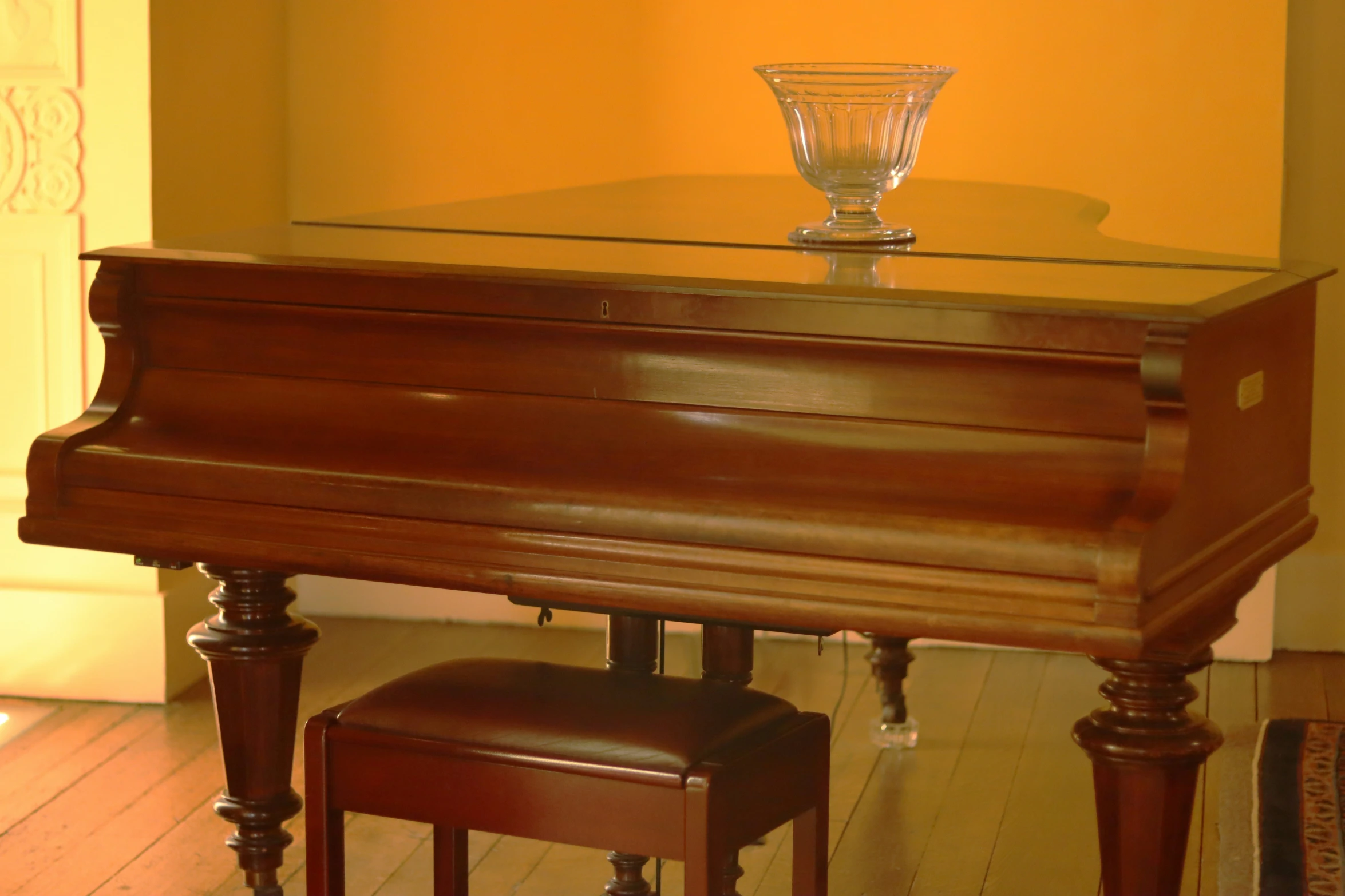 there is a glass sitting on top of a piano