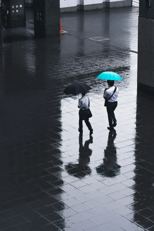 two people in suits walking down a rain soaked street