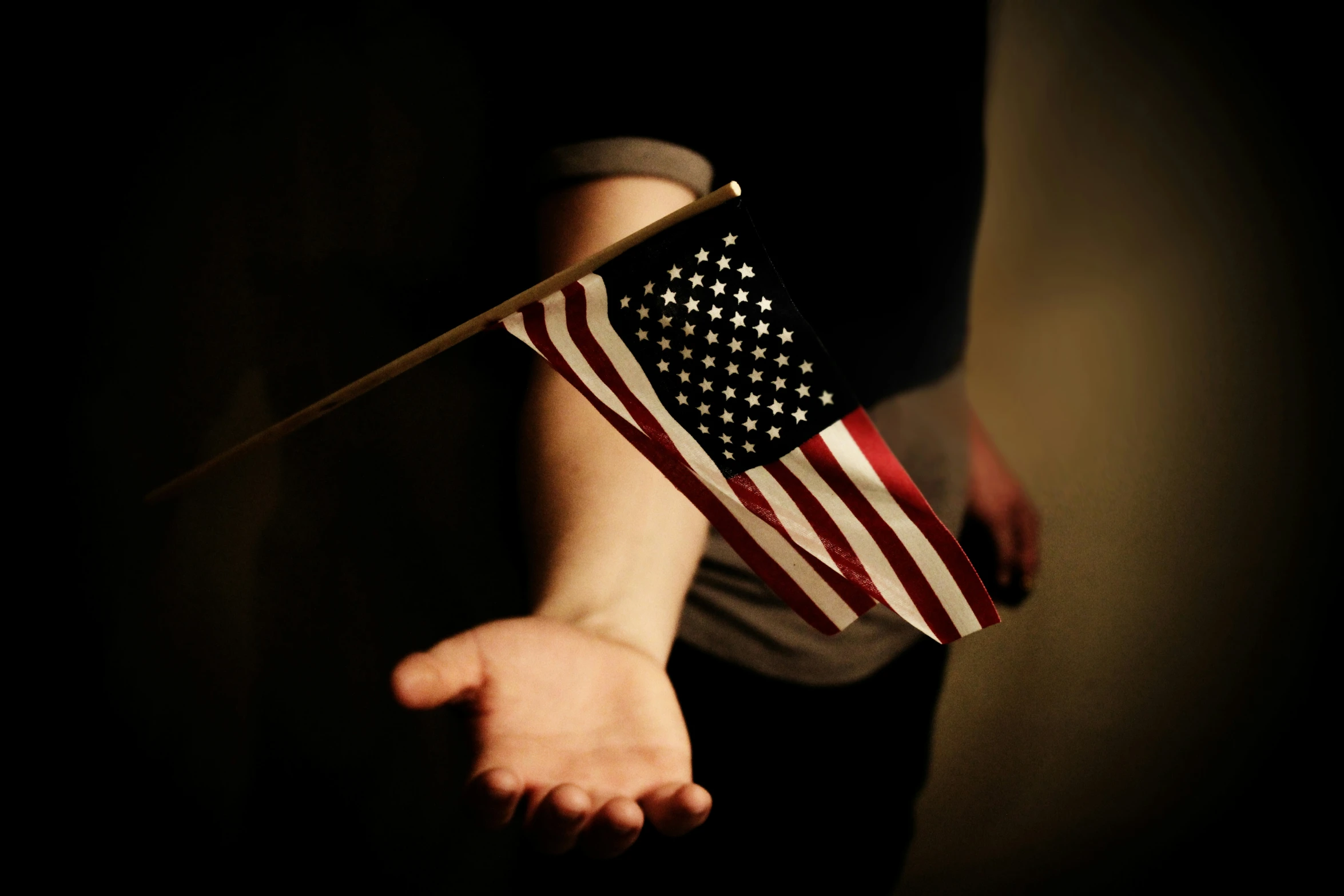 the american flag is on a stick in someones hands