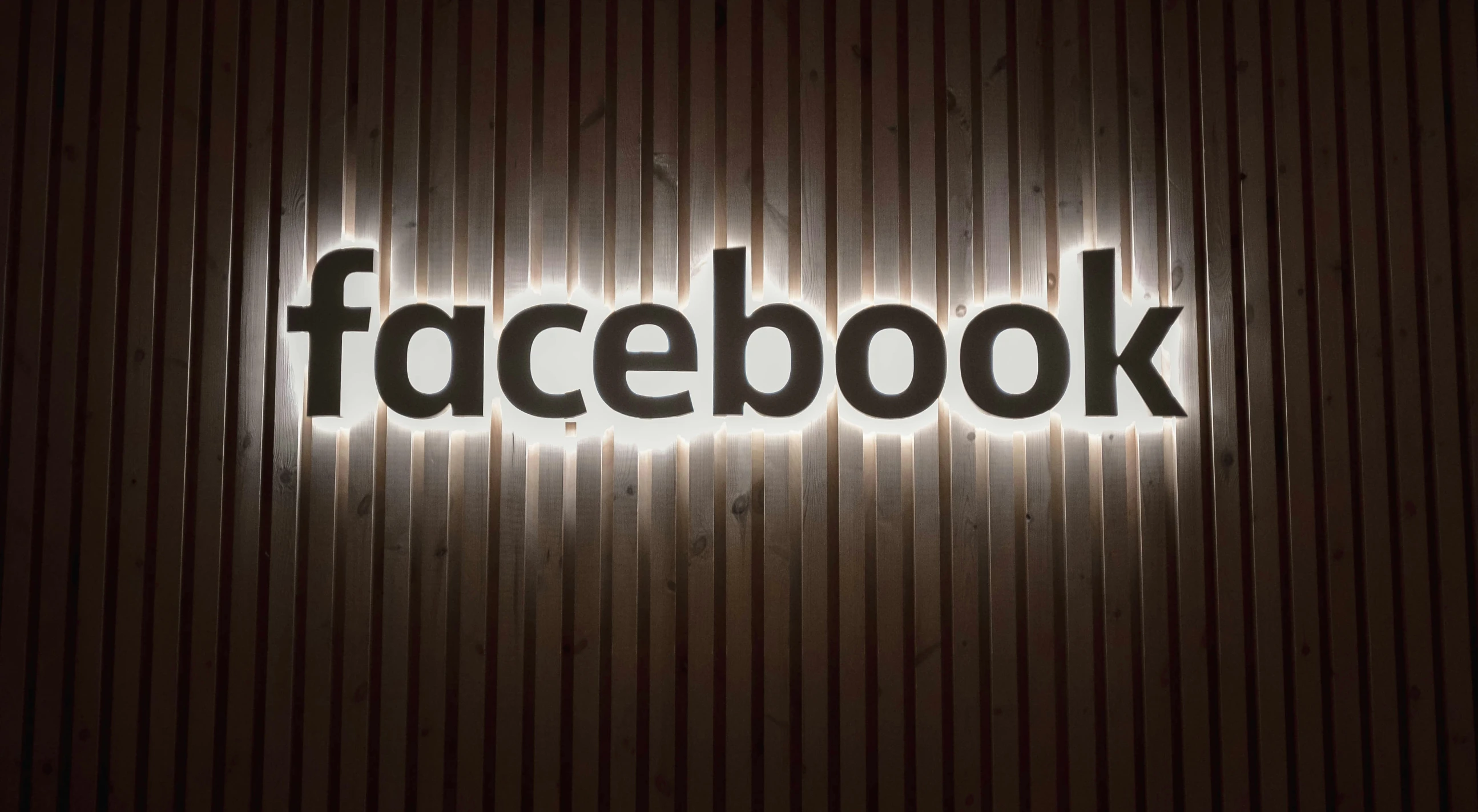 the facebook logo on the wall is lit by light