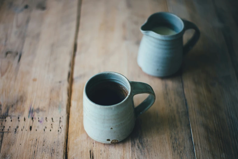 two pitchers, one is black and one white, sit on the floor