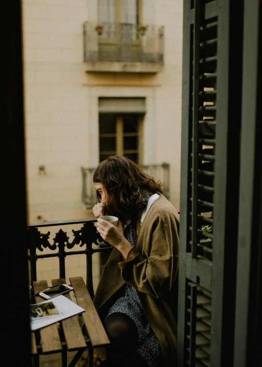 a woman sitting on a bench drinking coffee