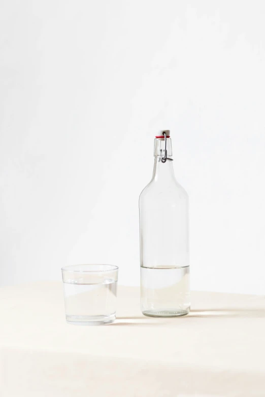 bottle with water and glass sitting on white counter