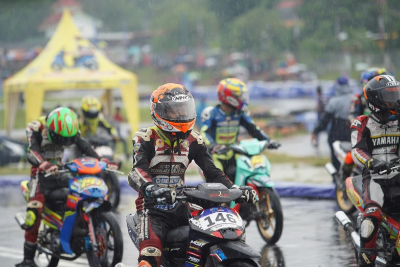 a group of people on motorcycles riding on a road in the rain