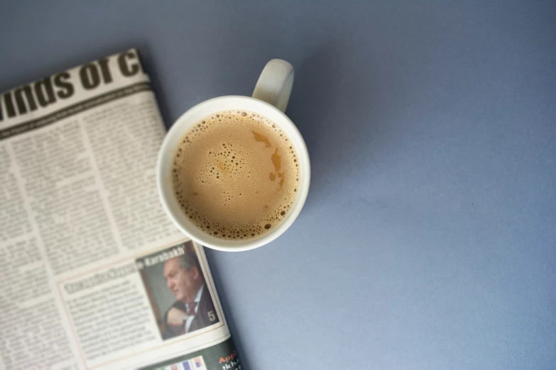 a cup of coffee sits in front of the newspapers