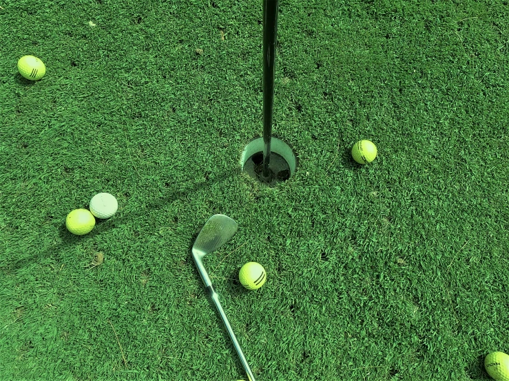 several yellow balls and golf clubs are laying on a green field