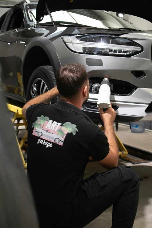 a man uses a foam glueer on the hood of a car