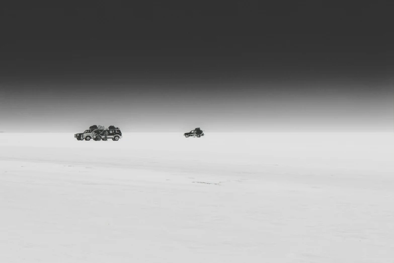 a couple of vehicles driving across a snow covered field