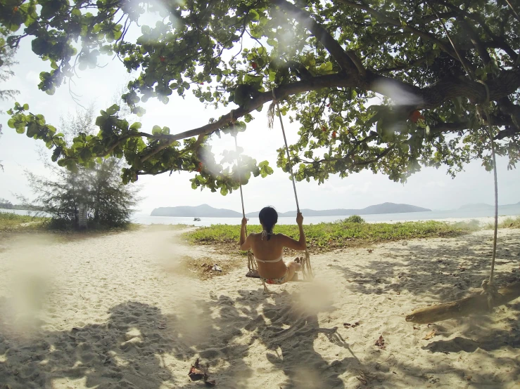 a woman sitting on a swing at the beach