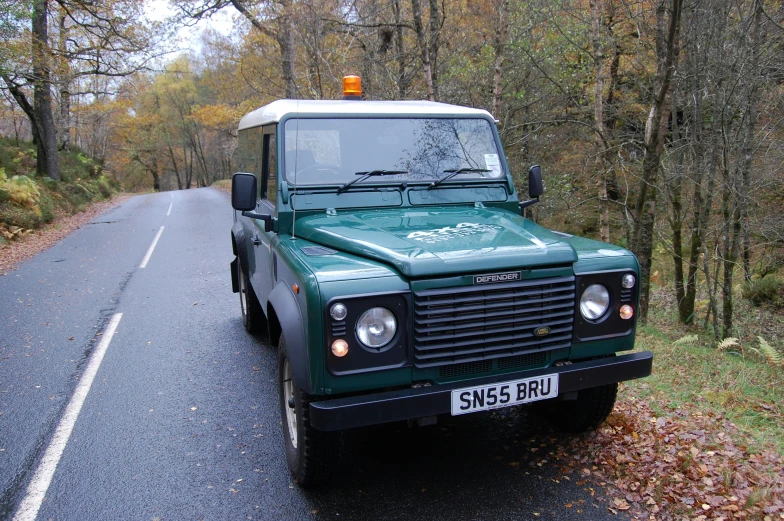 an older style green land rover sitting on the side of the road