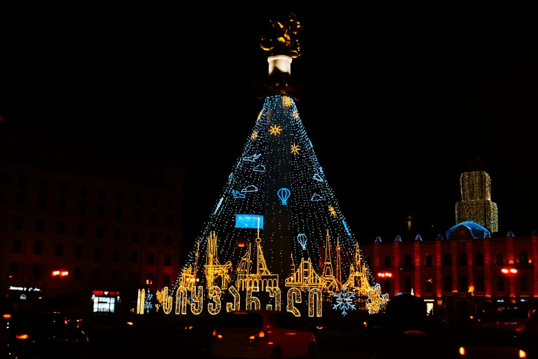 large lit - up christmas tree in the city at night