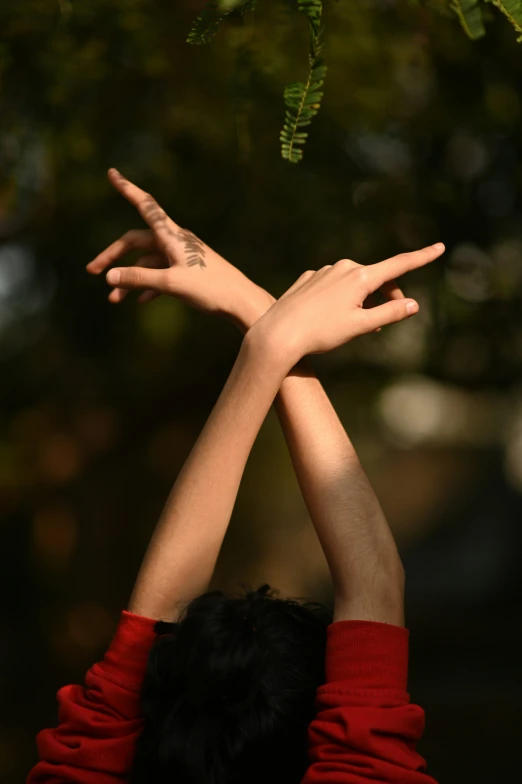 a woman who has her hands up with a tree in the background