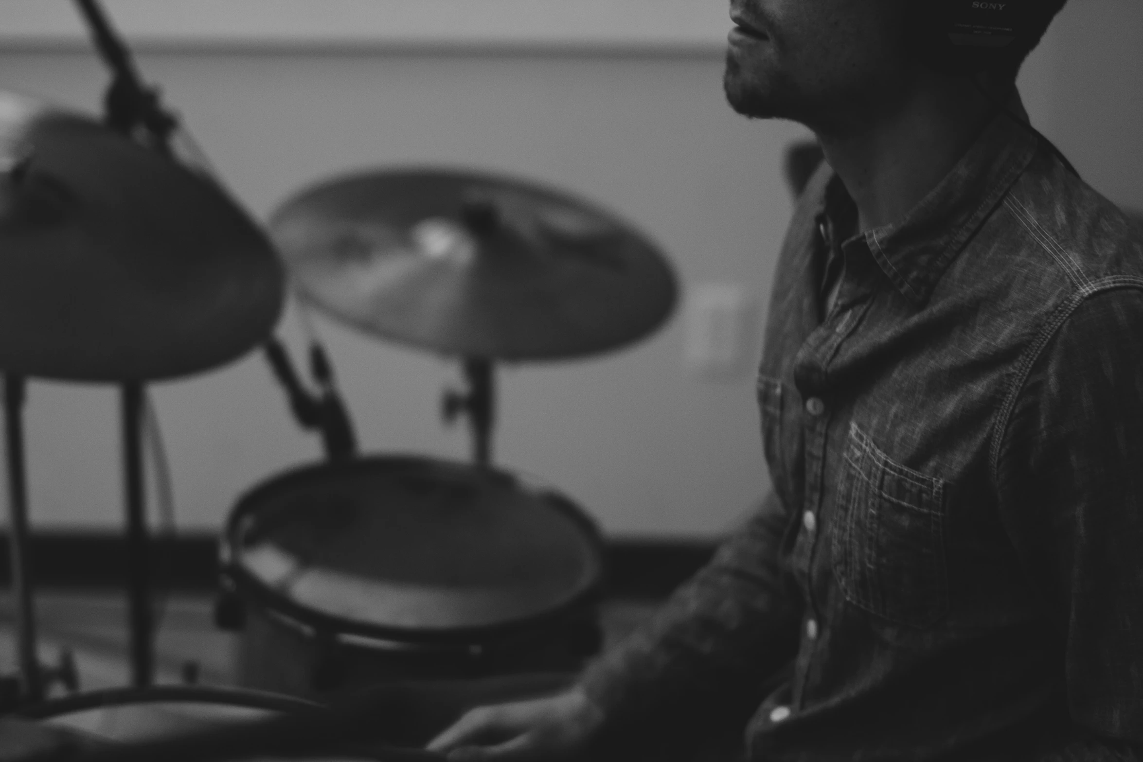 a man in jeans shirt playing drums in a room