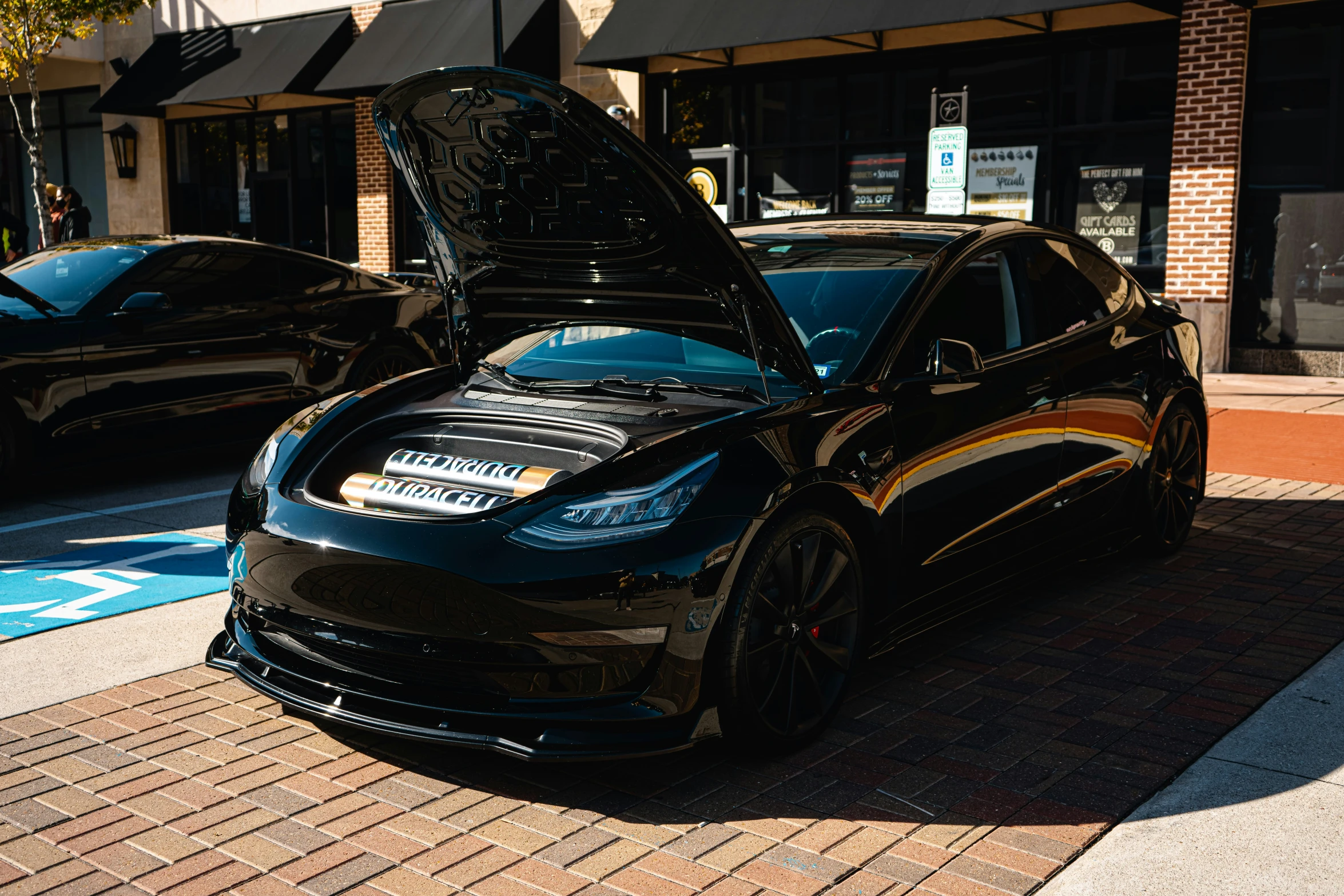 a black car with its hood open parked on the side of the road