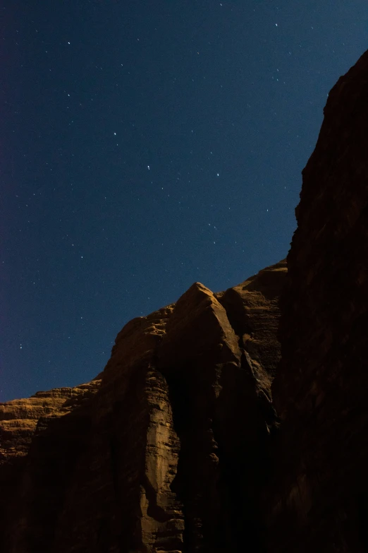 an upward view of some rocks with night sky in the background