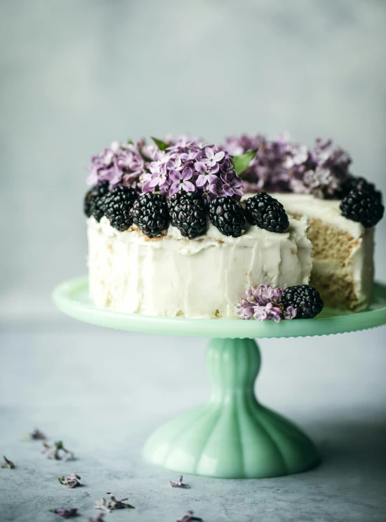 there is a small cake with lavender and blackberries on top