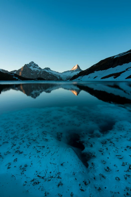 a lake is surrounded by mountains at dusk