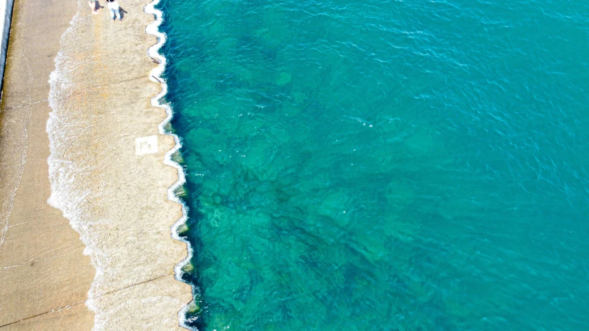 two people on a beach with the water crystal blue