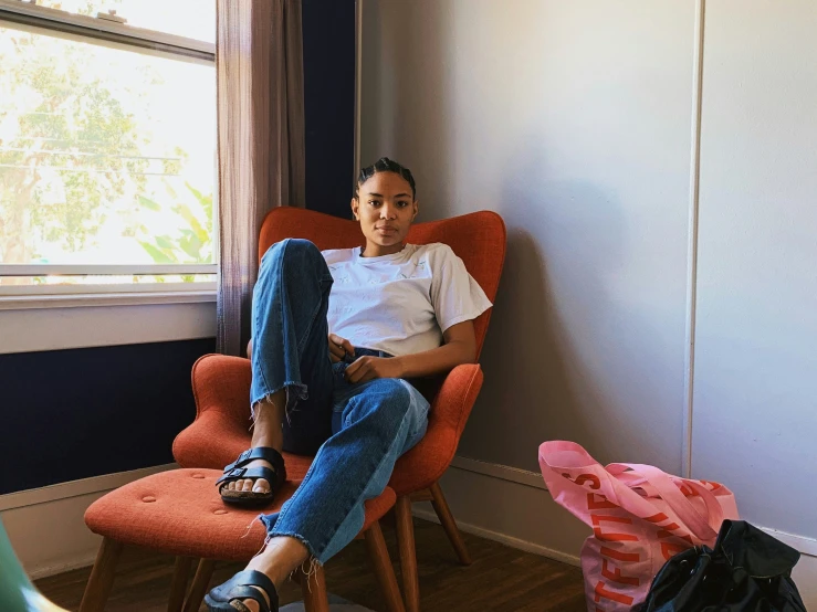 a man sitting in an orange chair in his bedroom