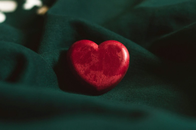 a red heart shaped object sitting on top of some green fabric