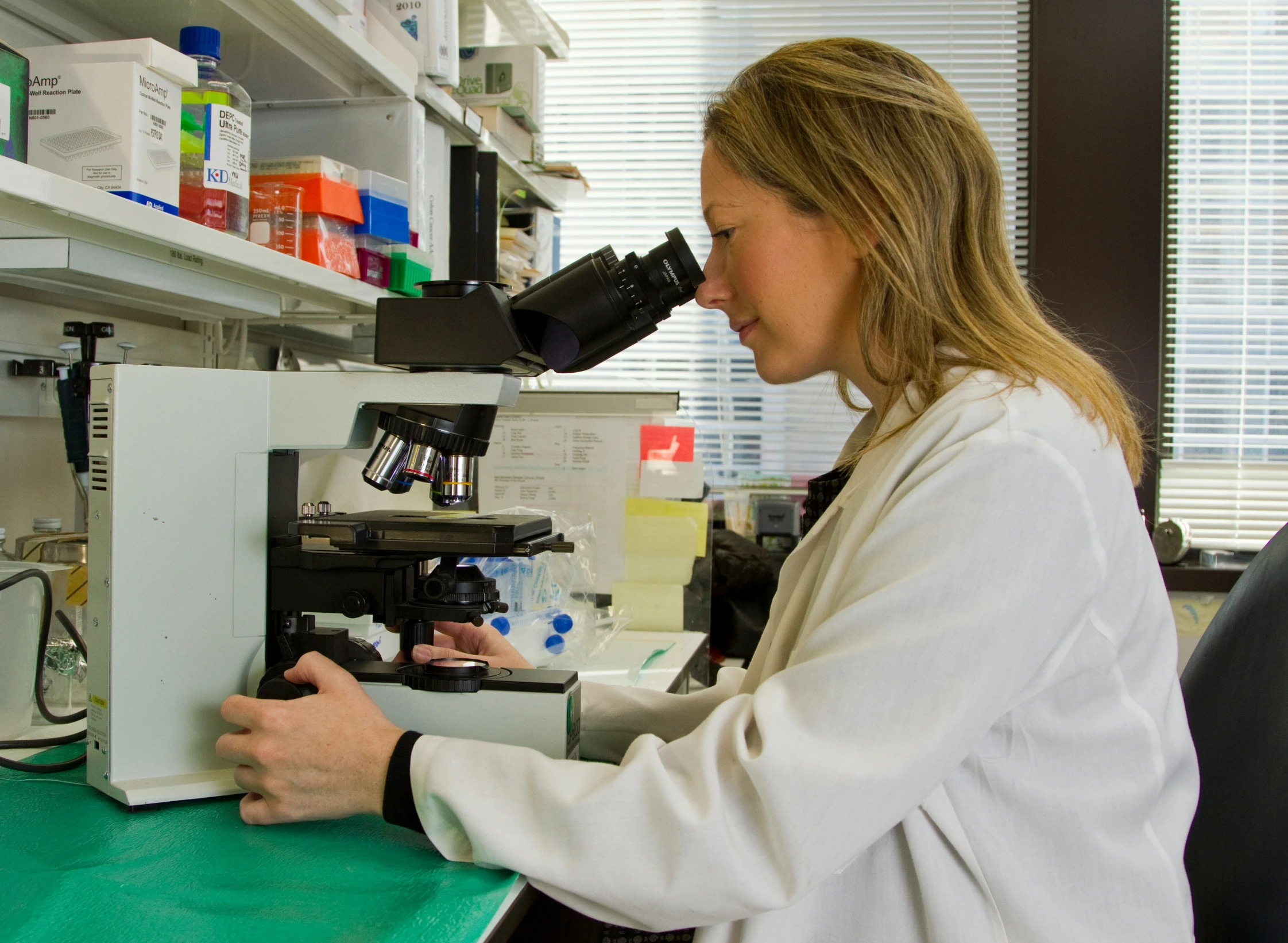 a young lady is looking at soing inside a microscope