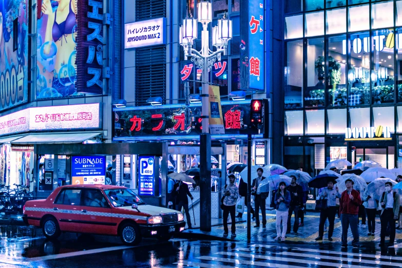 many people standing near an intersection at night with umbrellas