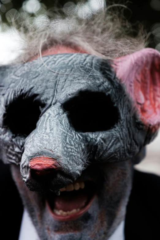 a man with gray makeup wearing an animal's mask