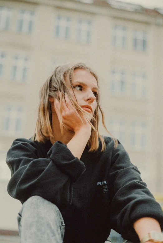 a woman wearing a black sweatshirt sitting on the ground