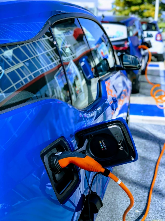 an electric vehicle plugging it's battery while other cars pass by