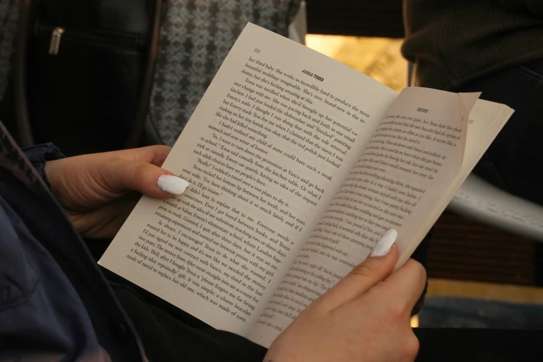 the person is reading the book while holding it in their hand