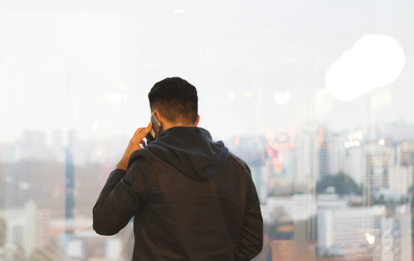 a man on the phone standing in front of a window