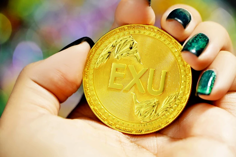 close up po of a person holding a gold token with the word dxu on it