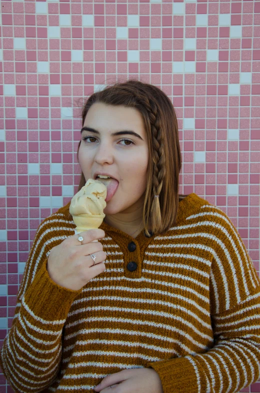 a woman standing in front of pink tiles biting into food